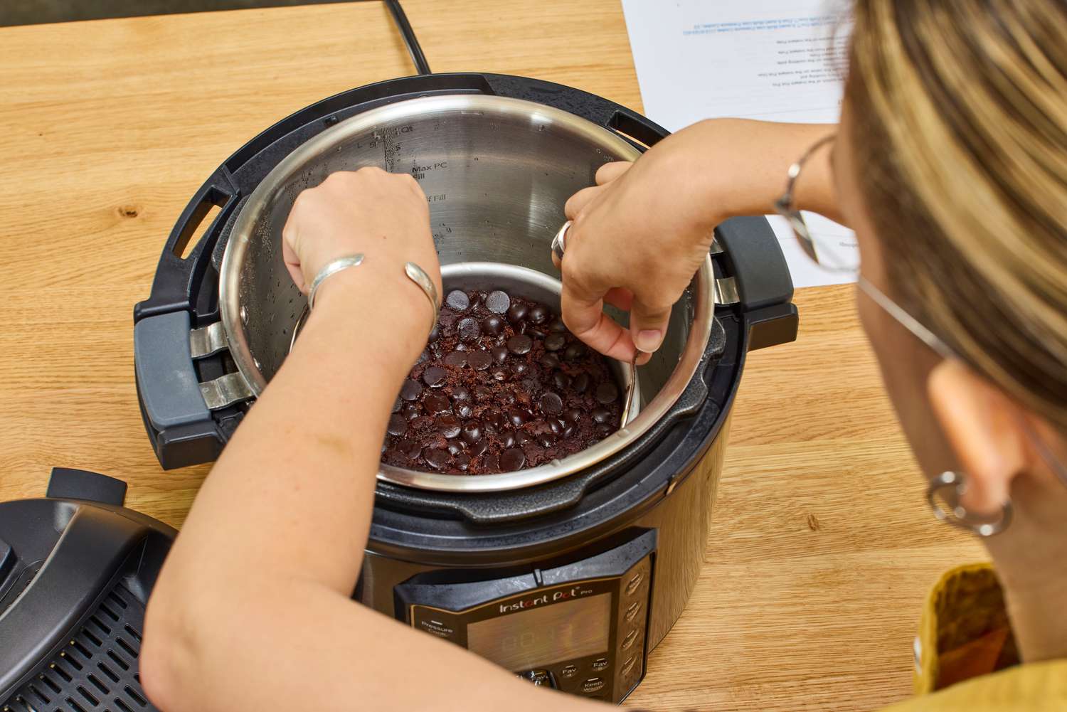 A person removes a cake from the Instant Pot Pro 10-in-1 6-Quart Pressure Cooker 