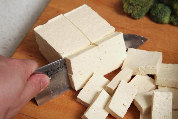 Cutting a block of firm tofu into squares.
