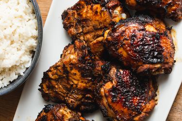 Closeup of grilled tamarind chicken thighs, served on a white platter.