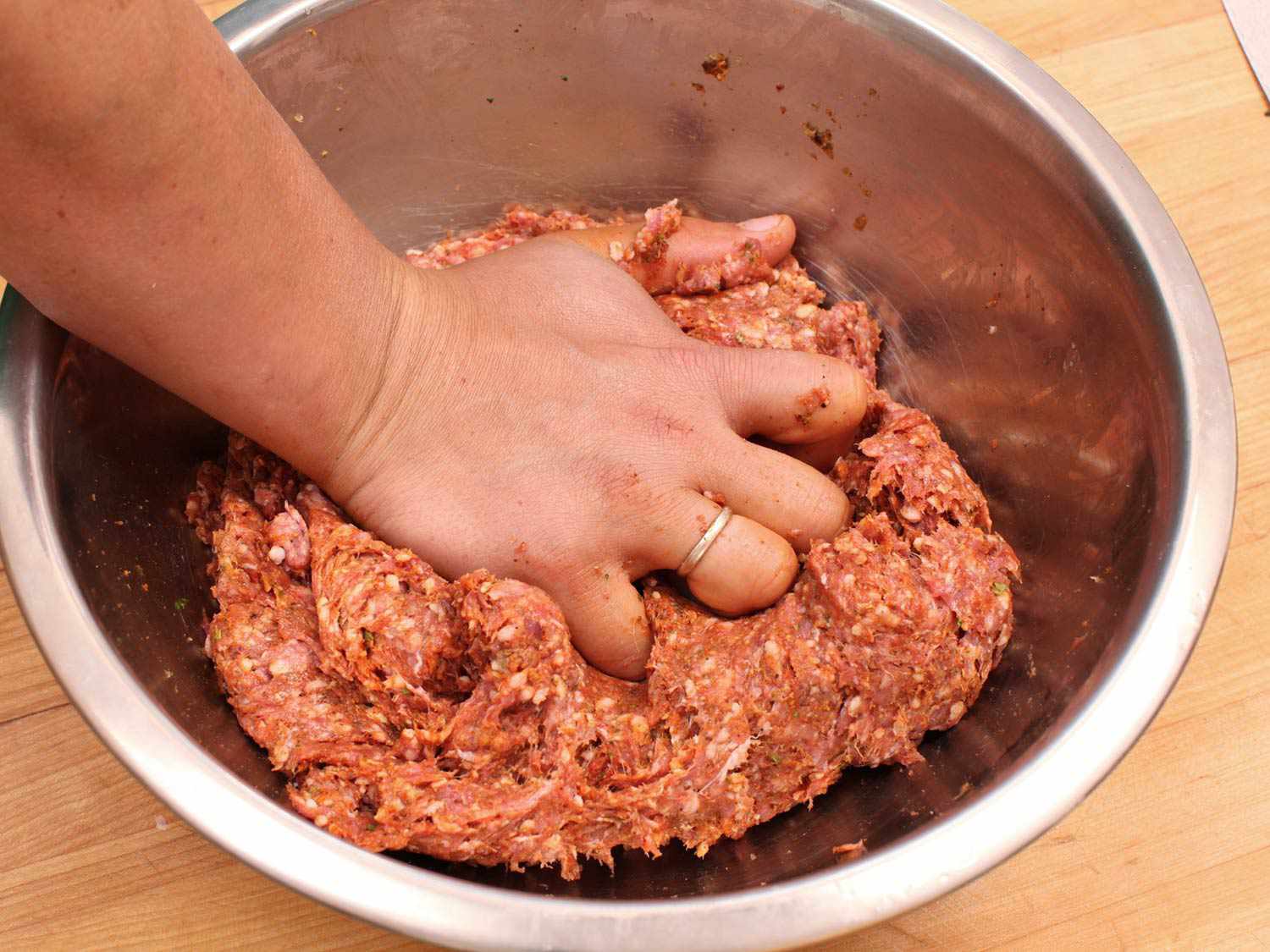 A hand pressing on a seekh kebab mixture. 