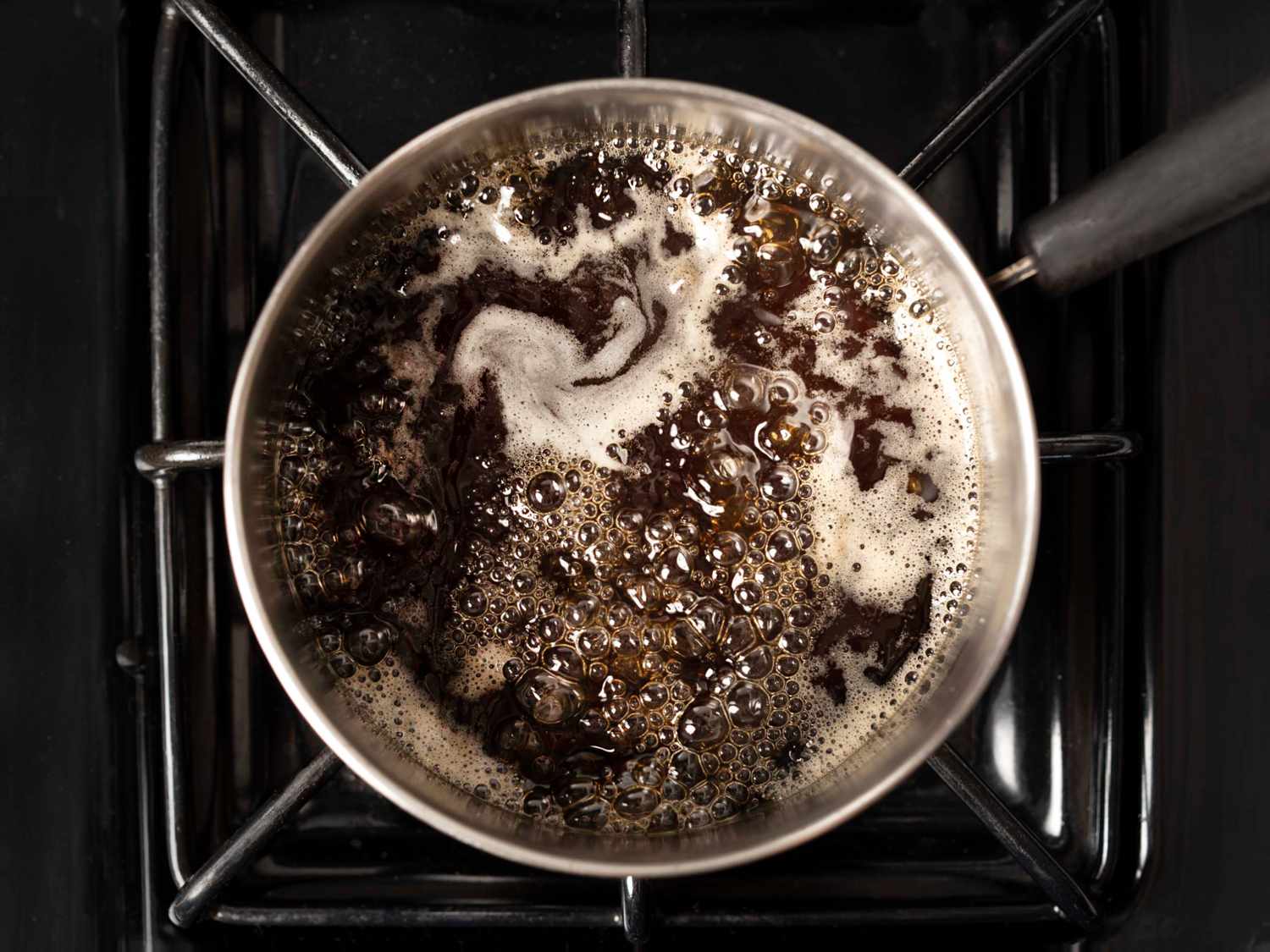 Turbinado sugar and water boiling on stovetop to make simple syrup.