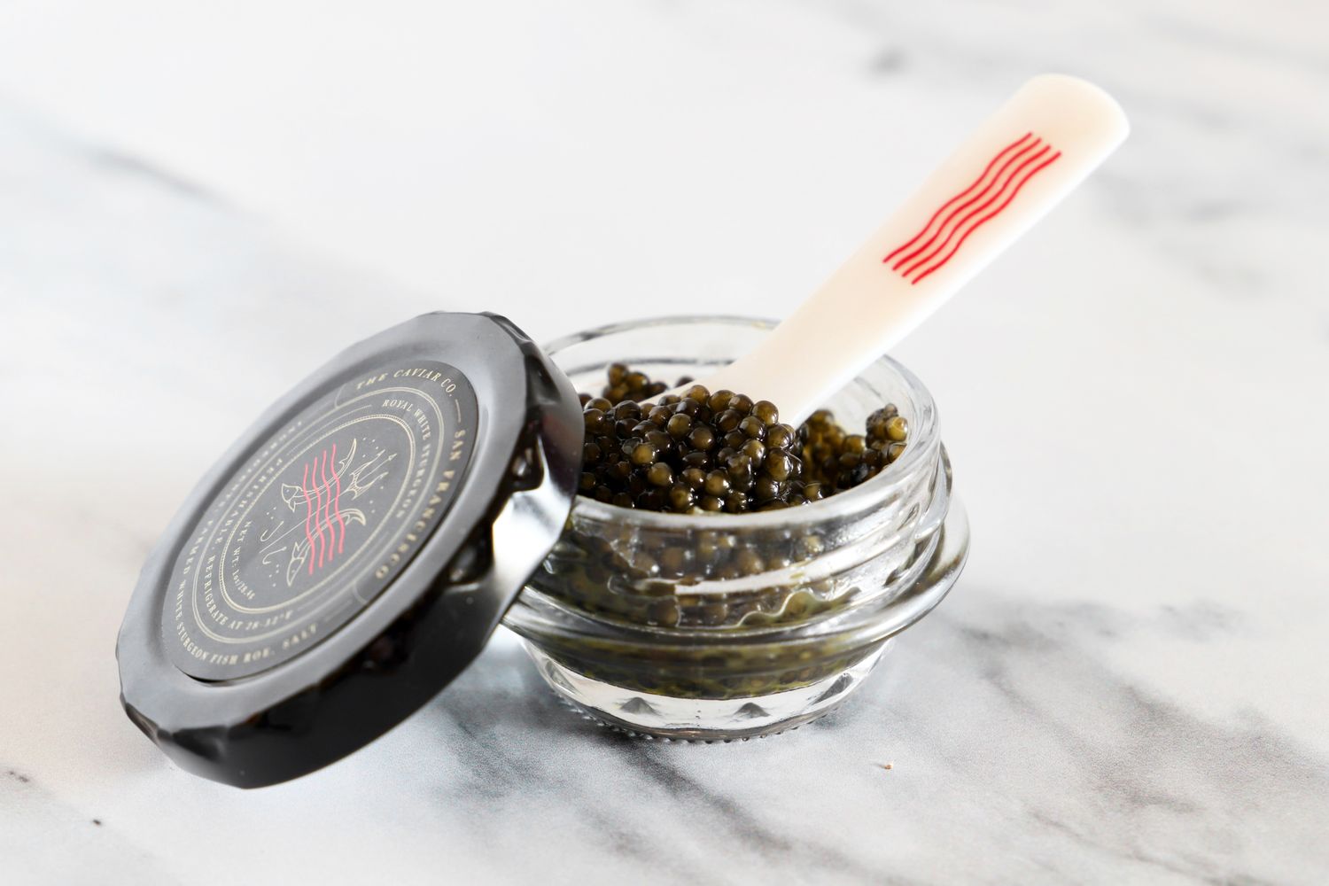 A tin of Caviar Co Royal white sturgeon caviar with a mother-of-pearl spoon inside