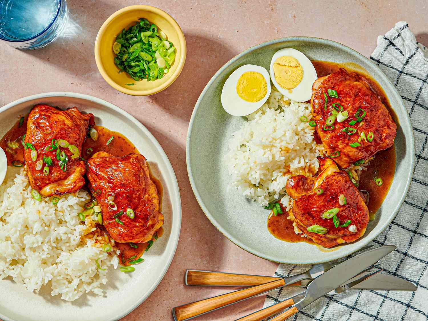 Roast chicken served with rice sauce and garnished with green onions on plates a halved boiled egg included on one plate