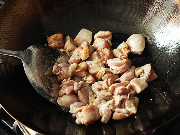 Stir-frying chicken in a wok for takeout-style kung pao chicken.
