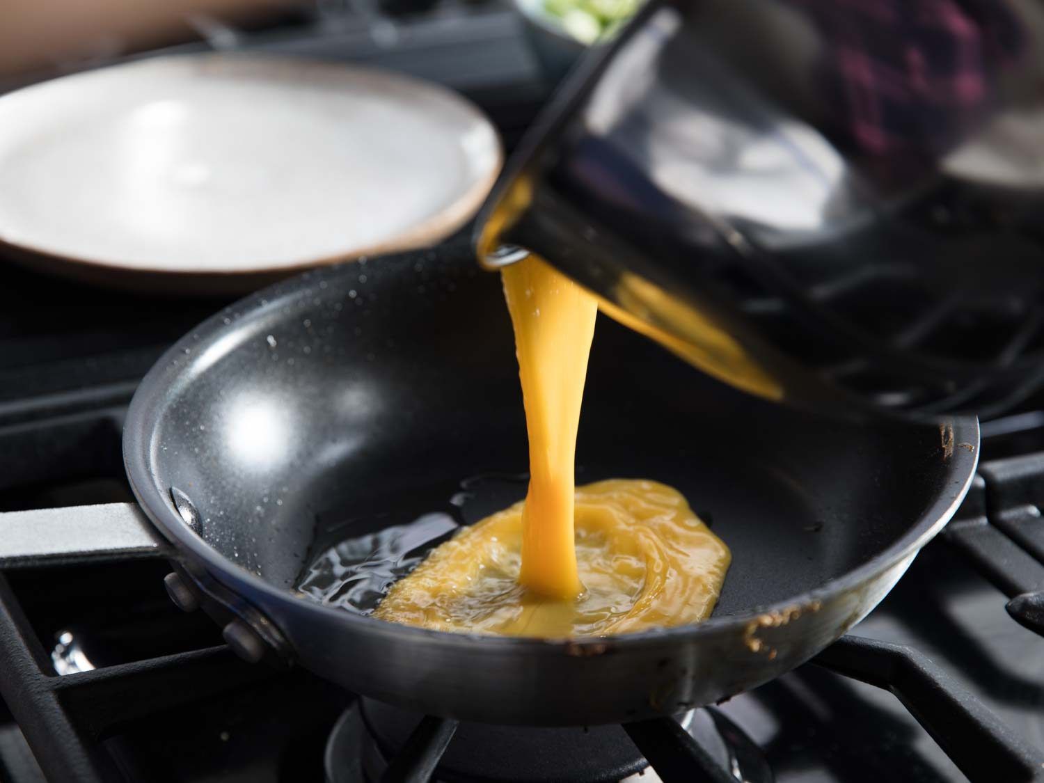 Beaten eggs being poured into a nonstick pan.