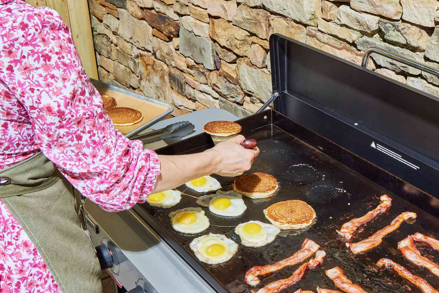 A person flips pancakes on the Weber 36 Inch Gas Griddle