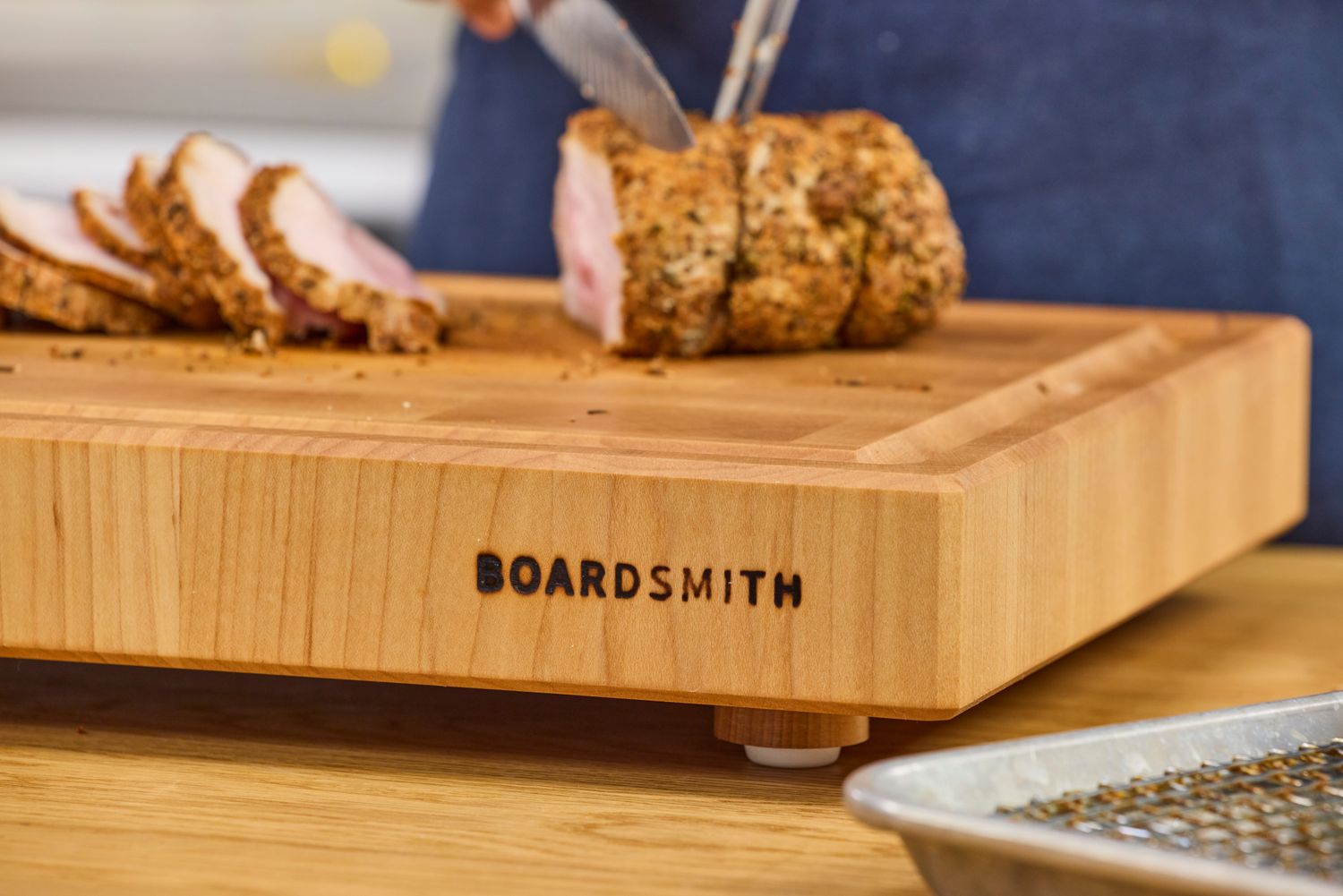 The Boardsmith Maple End-Grain Cutting Board holding a sliced roast being carved by someone