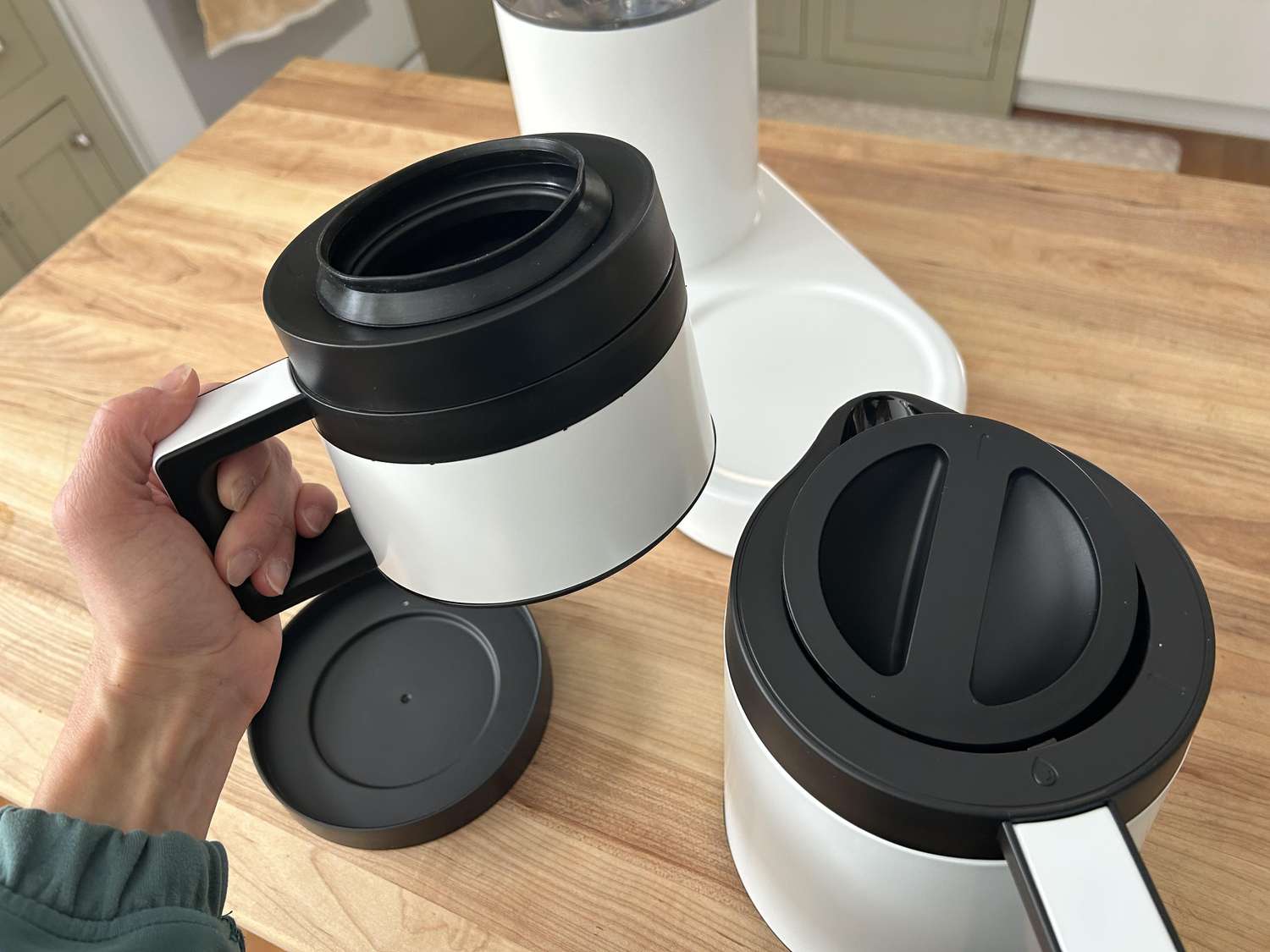 A hand holding the brew basket of the Ratio Six coffee maker next to the carafe.