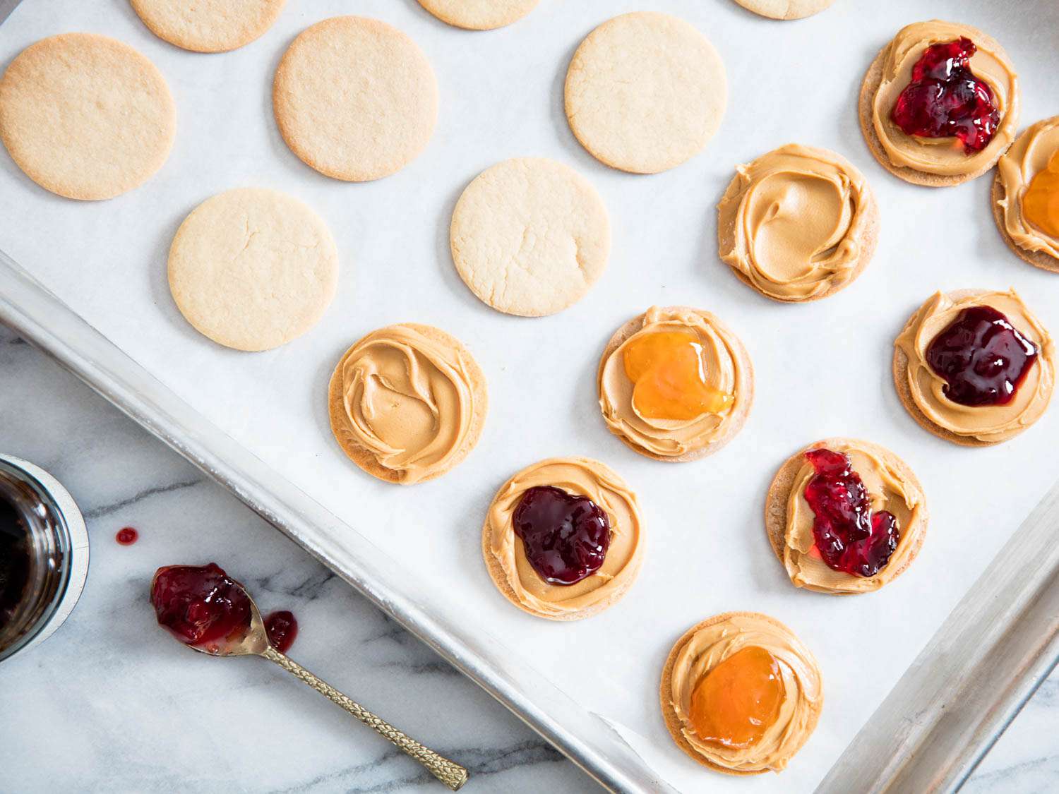 Overhead view of cookies being filled with peanut butter and jelly.