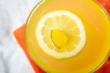 A mezcal pickle lemonade garnished with a slice of lemon and pickle piece top view