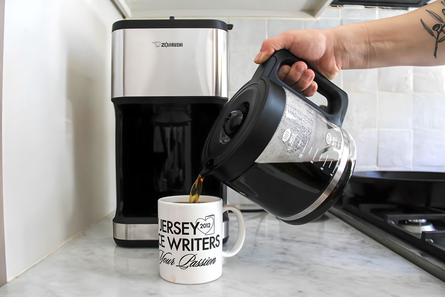 A person pouring coffee from a Zojirushi coffee maker