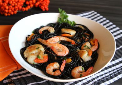 A bowl of black squid ink pasta with shrimp and scallops 