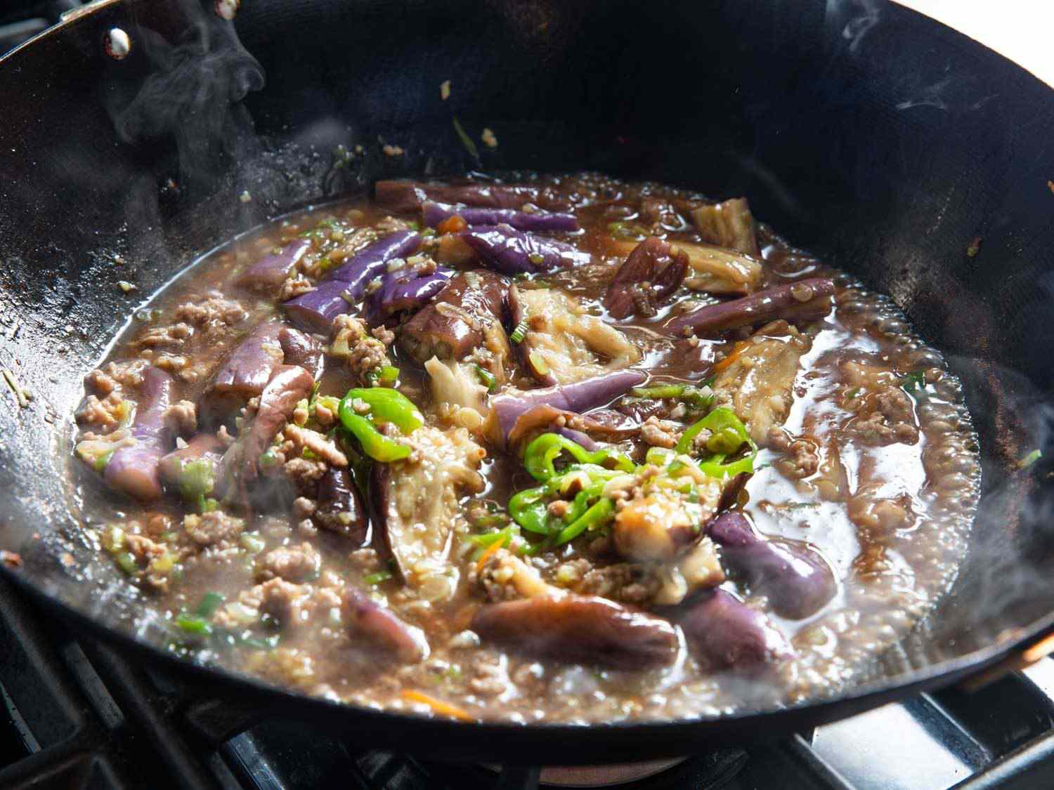 Sichuan eggplant simmering in a wok.