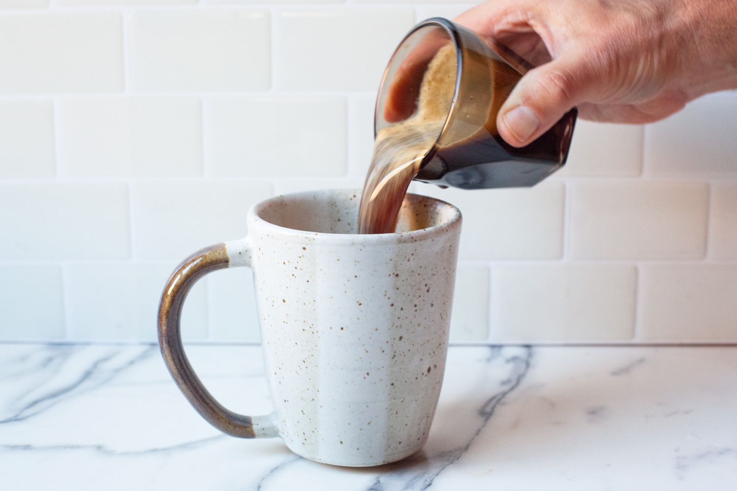 An espresso shot being poured into a coffee mug