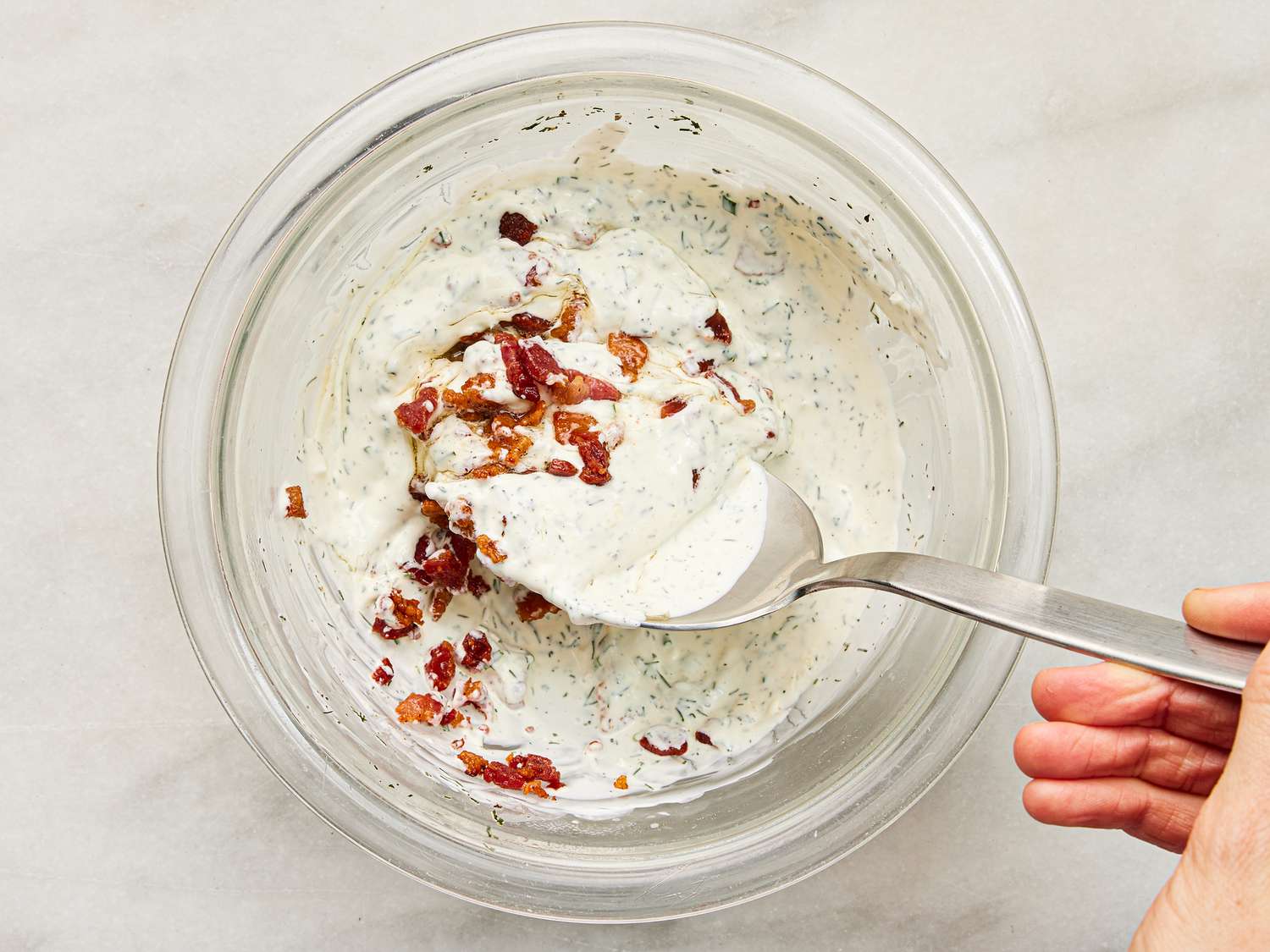 Mixing bacon into dip in a small bowl 