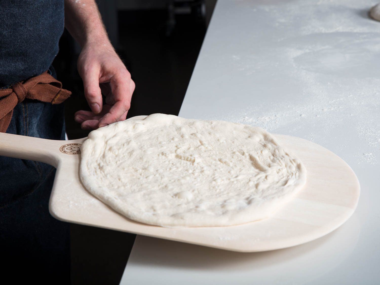 Stretched pizza dough on a peel, ready to be topped.
