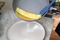 A spatula scooping food out of the Caraway Nonstick Ceramic Frying Pan onto a plate