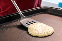 A person using the Tovolo Silicone Slotted Turner to flip a pancake