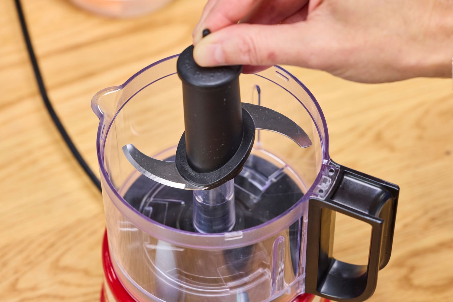 A person places a blade into the KitchenAid 3.5-Cup Food Chopper