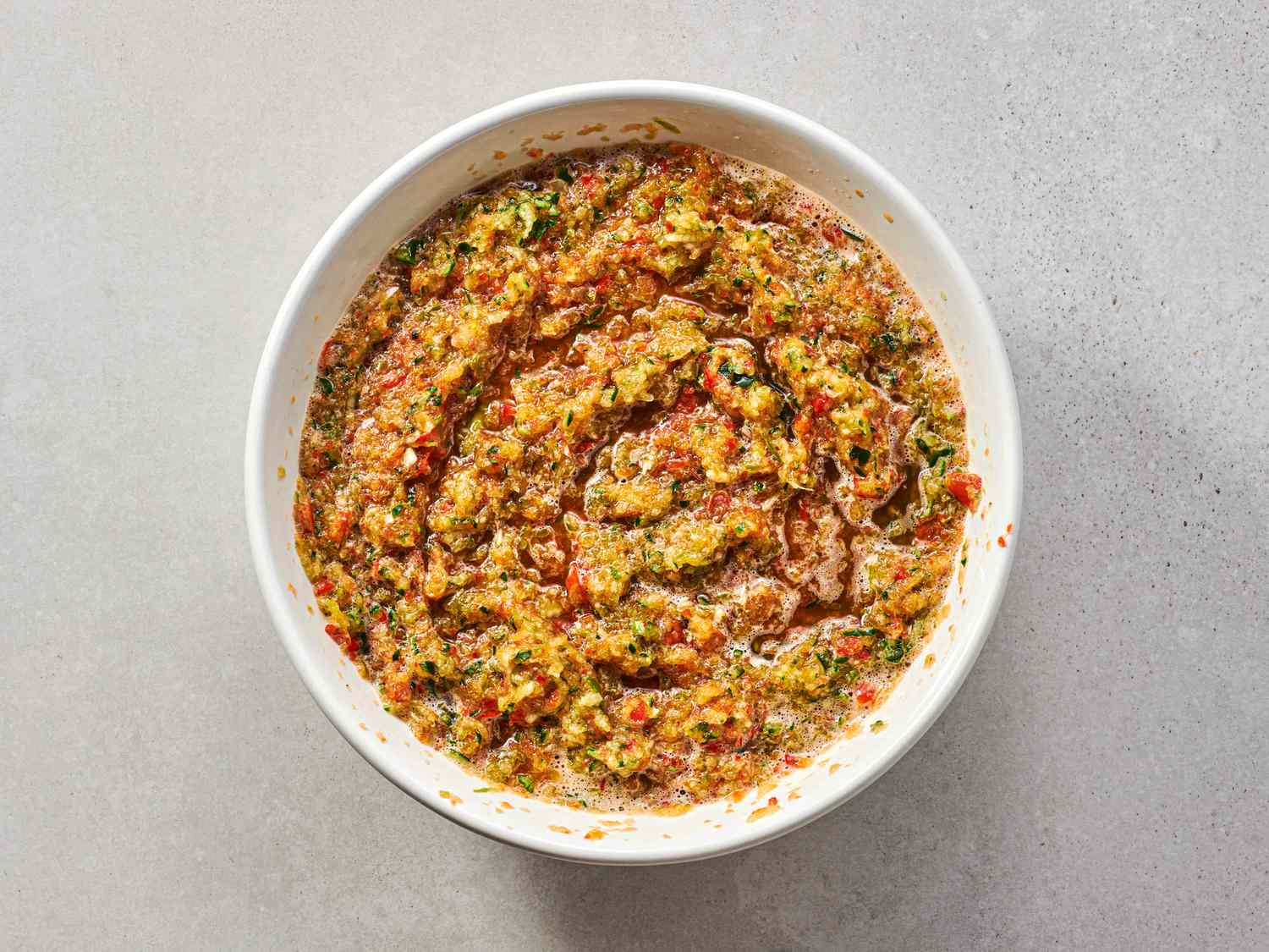 Chopped cucumbers, onions, and peppers mixed in salt inside a medium bowl
