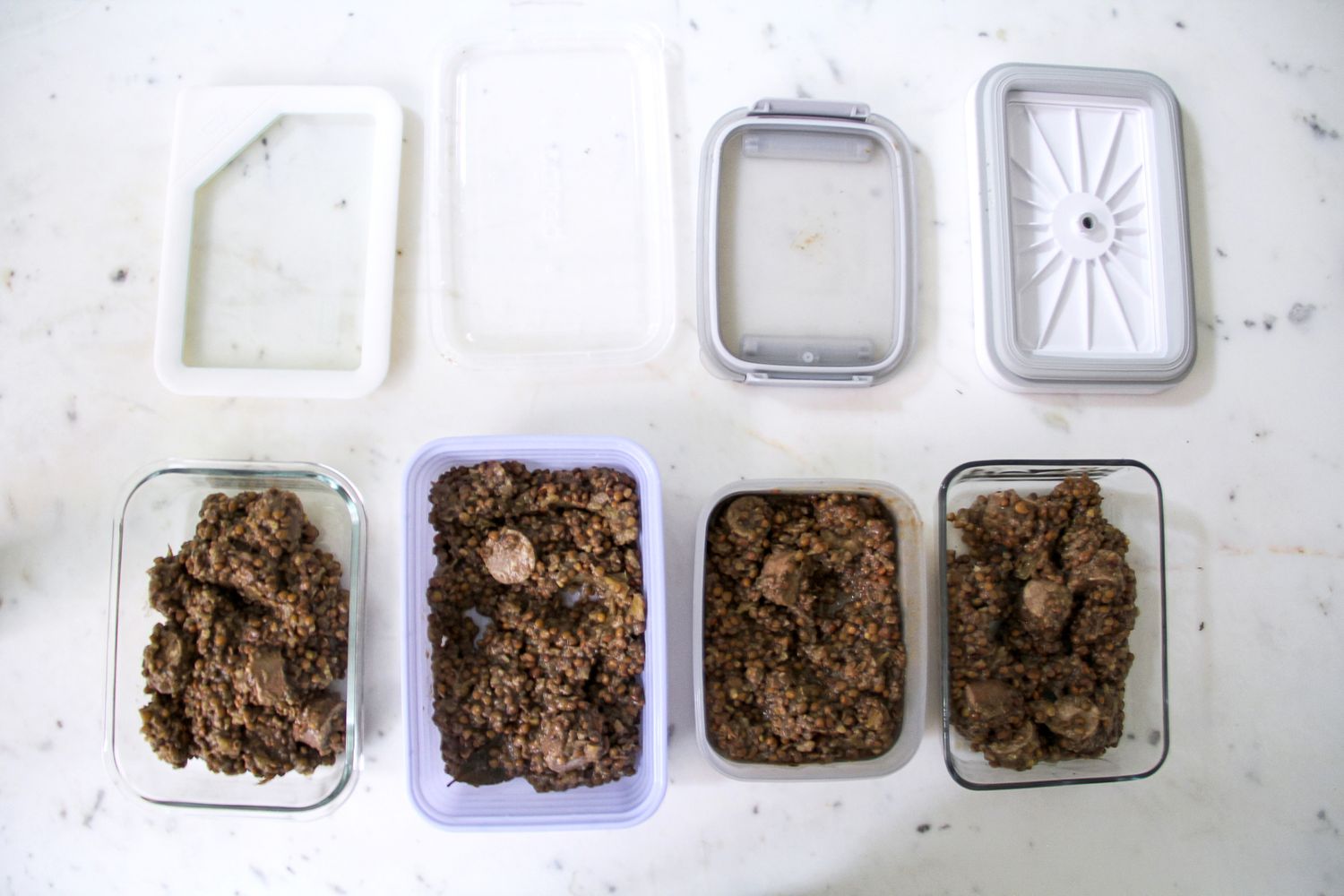 Prepared lentil dishes in multiple reusable containers with lids arranged on a counter