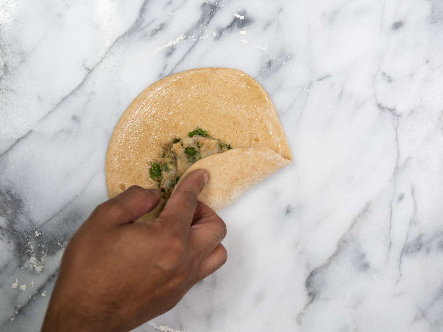 Author fills a paratha with the potato mixture on a marble slab.