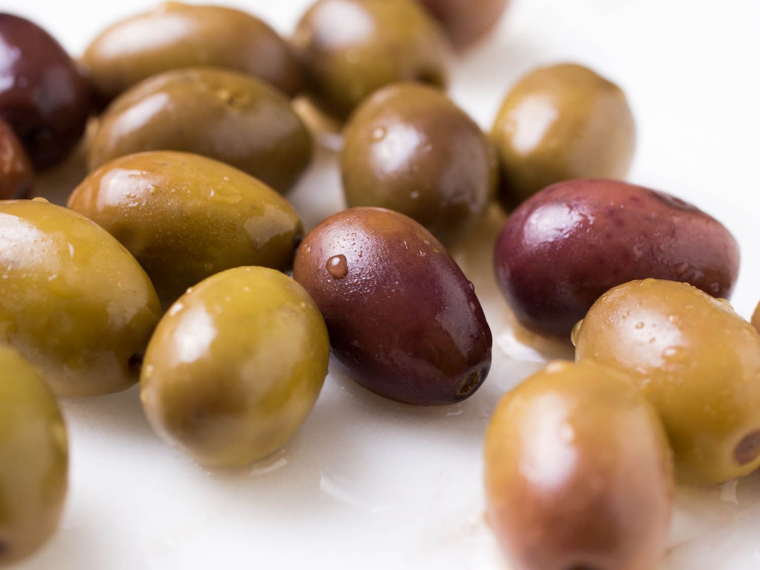 Closeup of green and brown olives covered in drops of olive brine