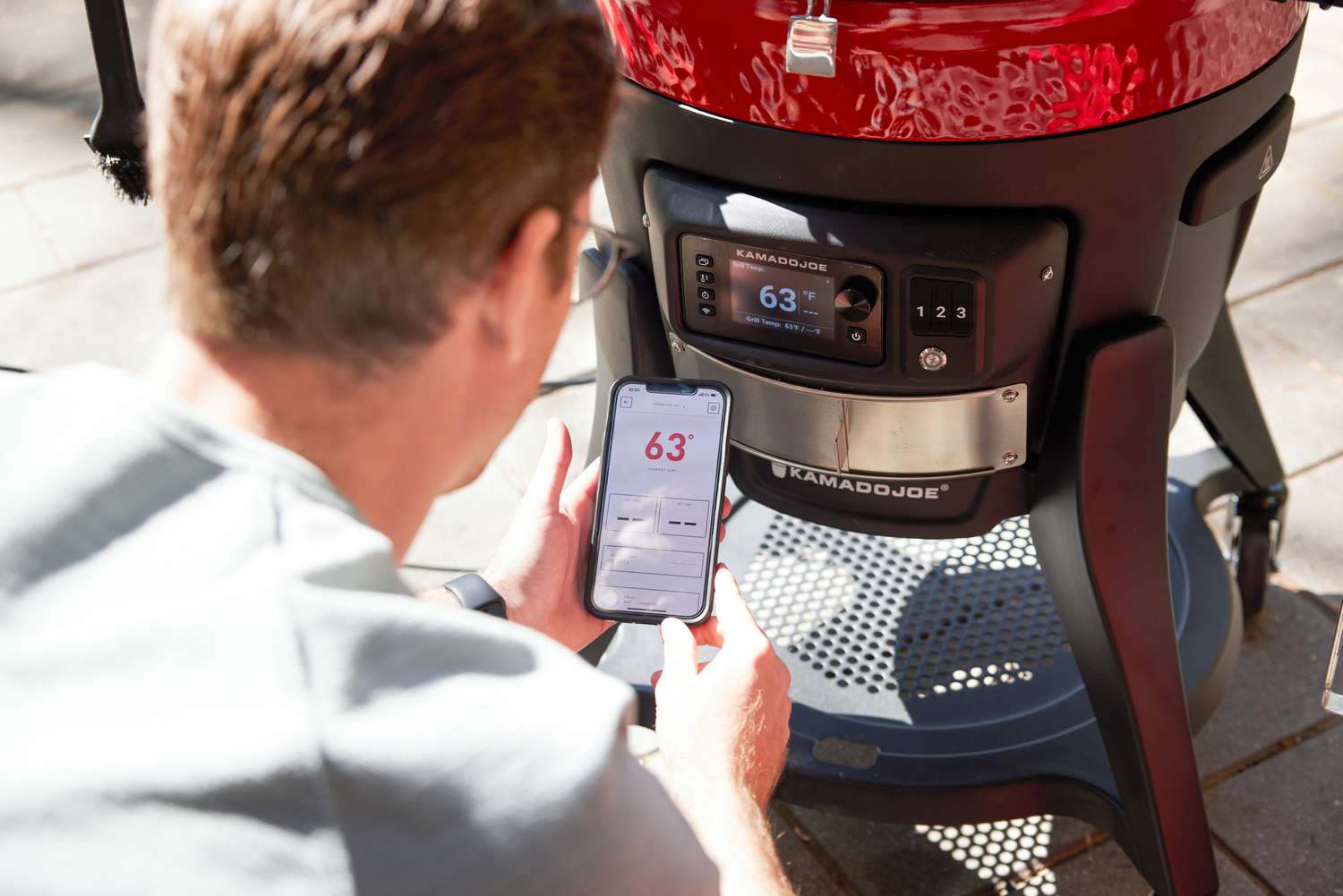 a person standing in front of the Konnected Joe and using the kamado's app