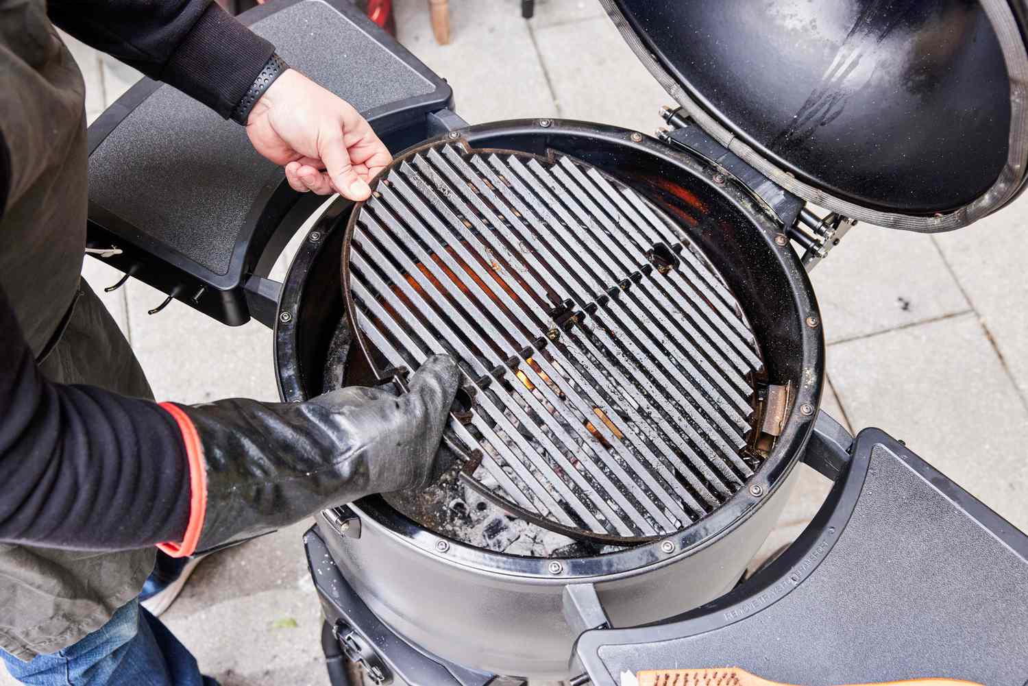 A person places a metal grill into the Broil King Keg Kamado Charcoal Grill