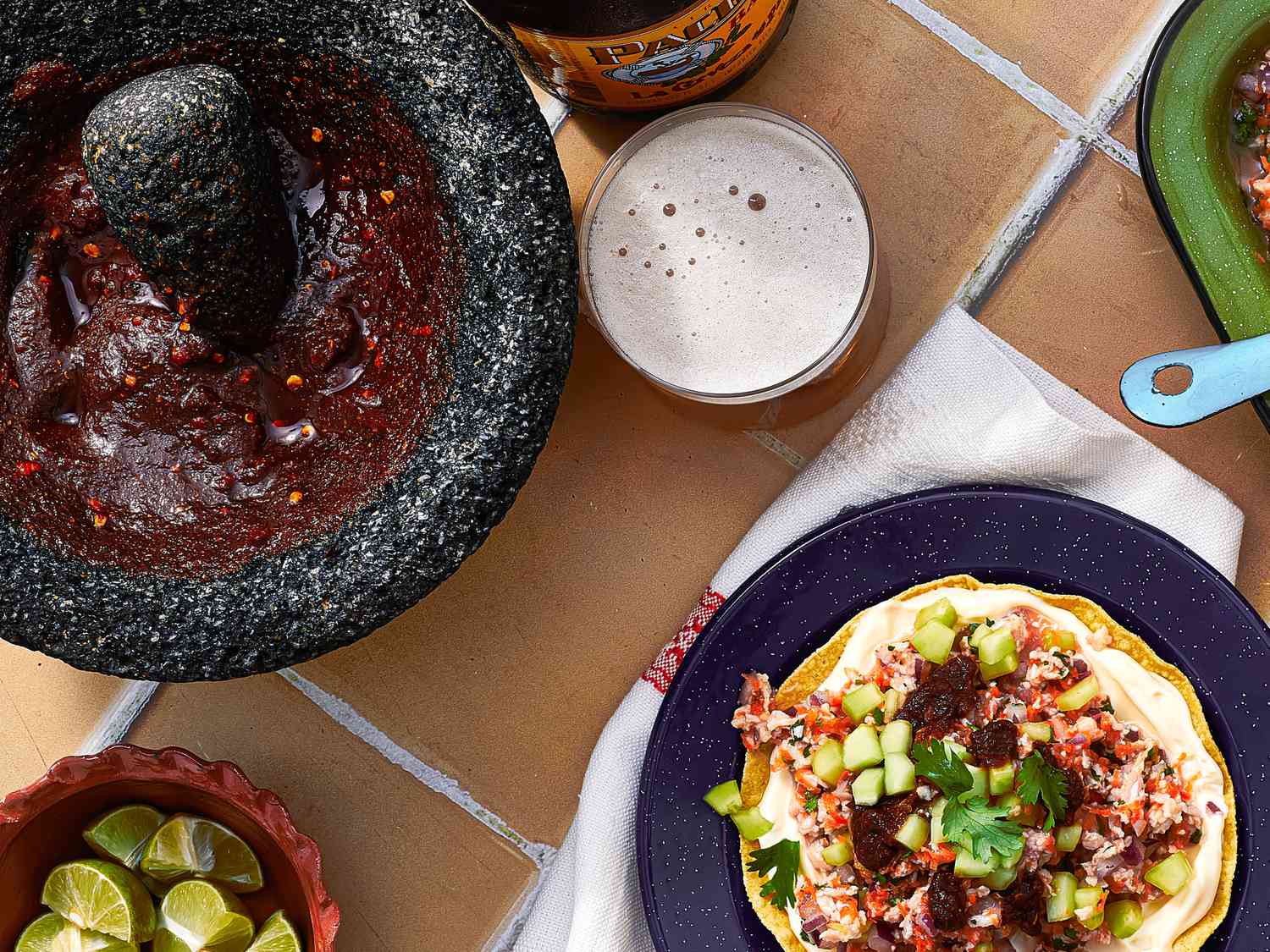Overhead view of salsa negra in a molcajete on a table with a ceviche tostada 