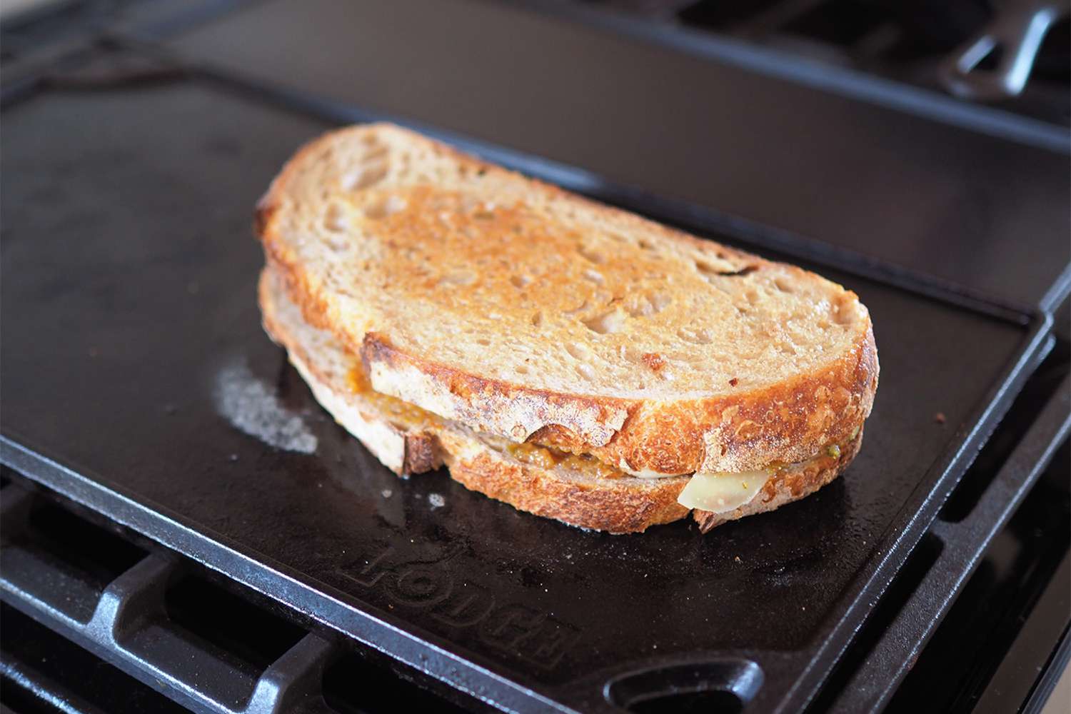 Lodge Reversible griddle with a grilled cheese on top with slightly toasted bread