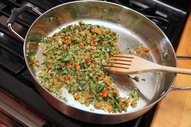 The herb-flecked soffritto is stirred in the pan.