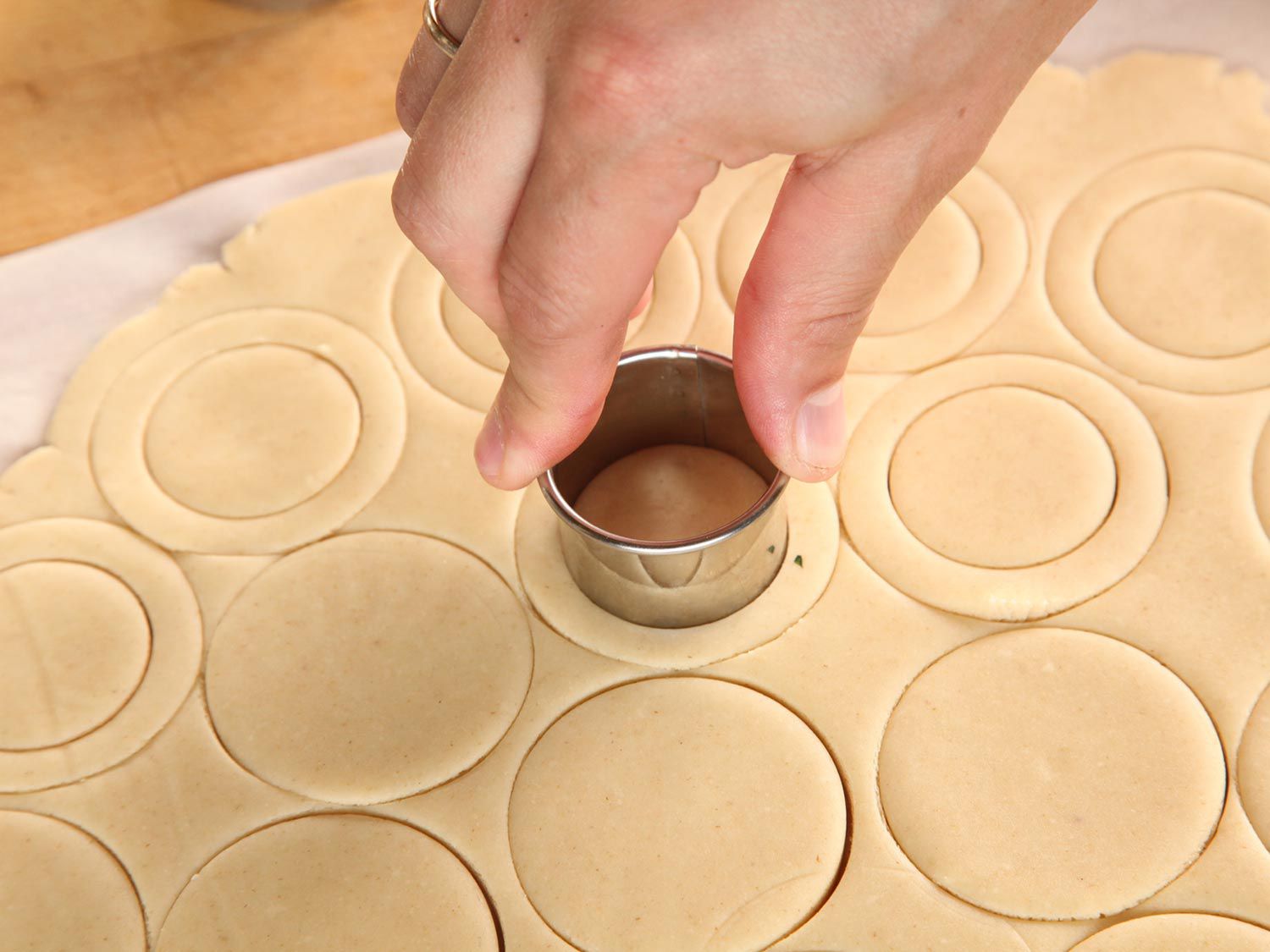 Cutting out cookie rounds in two concentric circles, one larger than the other. 