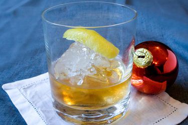 An apple brandy old fashioned, flanked by a Christmas tree ornament.