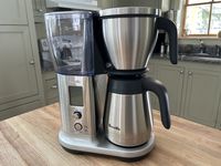 The Breville Precision coffee maker on a wooden table in a kitchen.