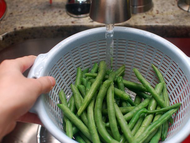 Running cold water over blanched green beans in colander