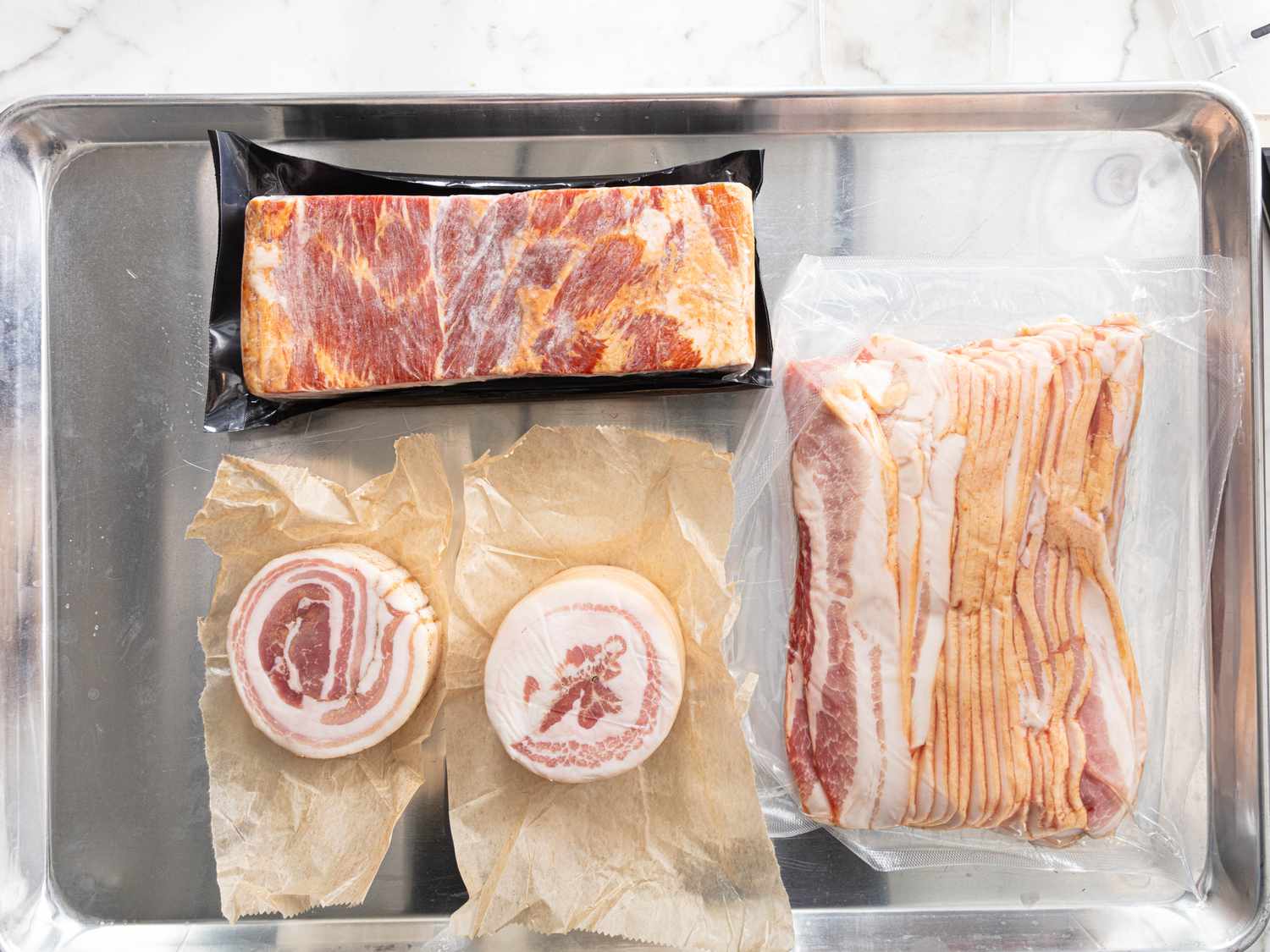 Overhead of partially frozen variety of bacon, pancetta and lardon 