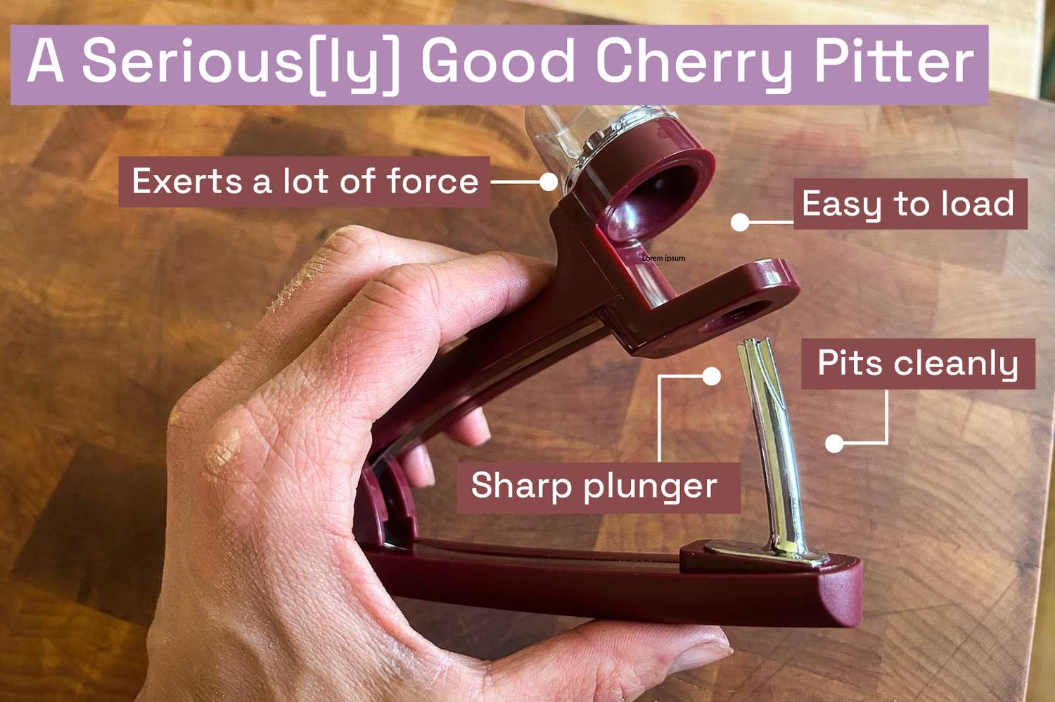 A hand holding the OXO cherry pitter above a wooden cutting board