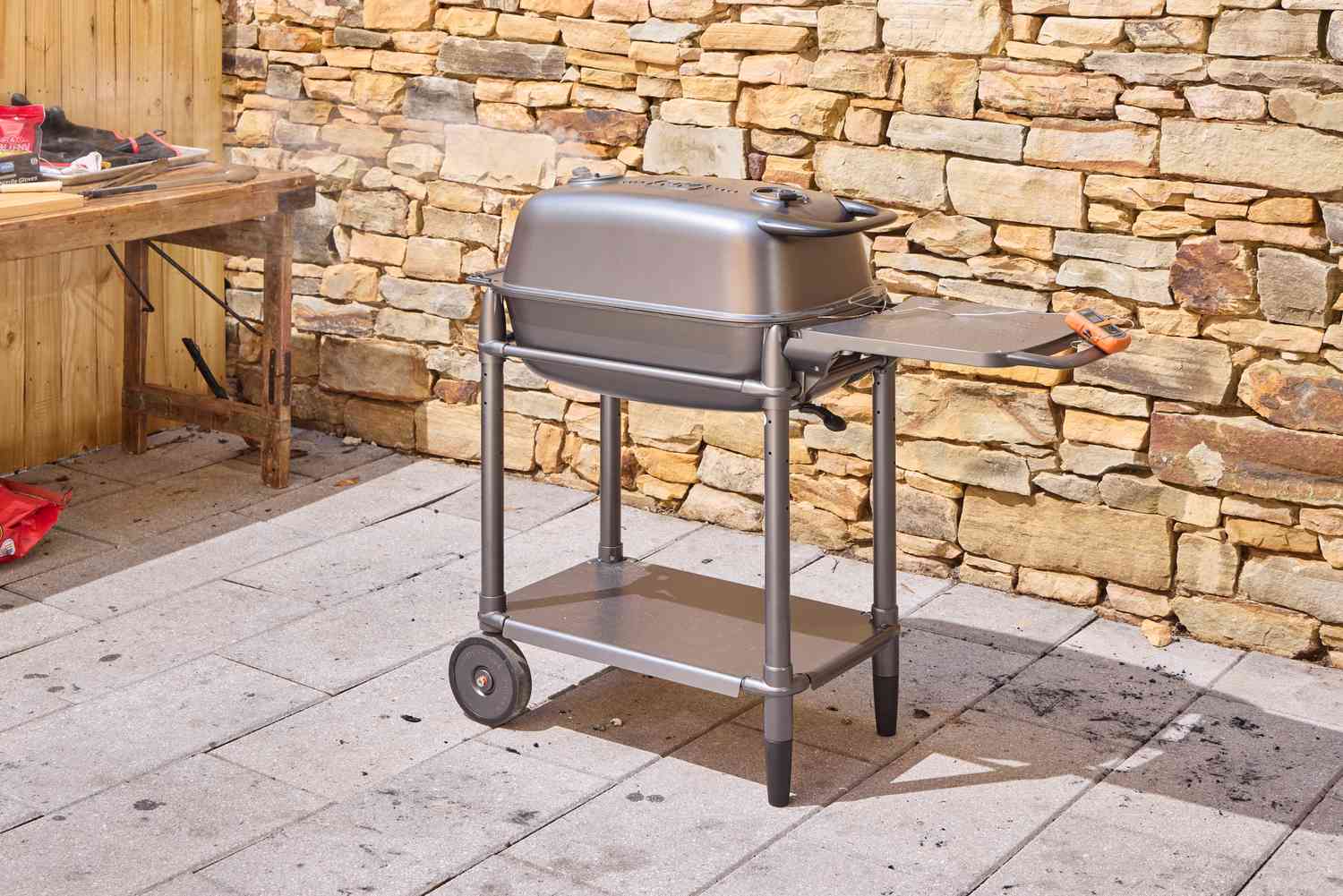 The PK Grills Original PK300 Grill & Smoker outdoors near stone wall