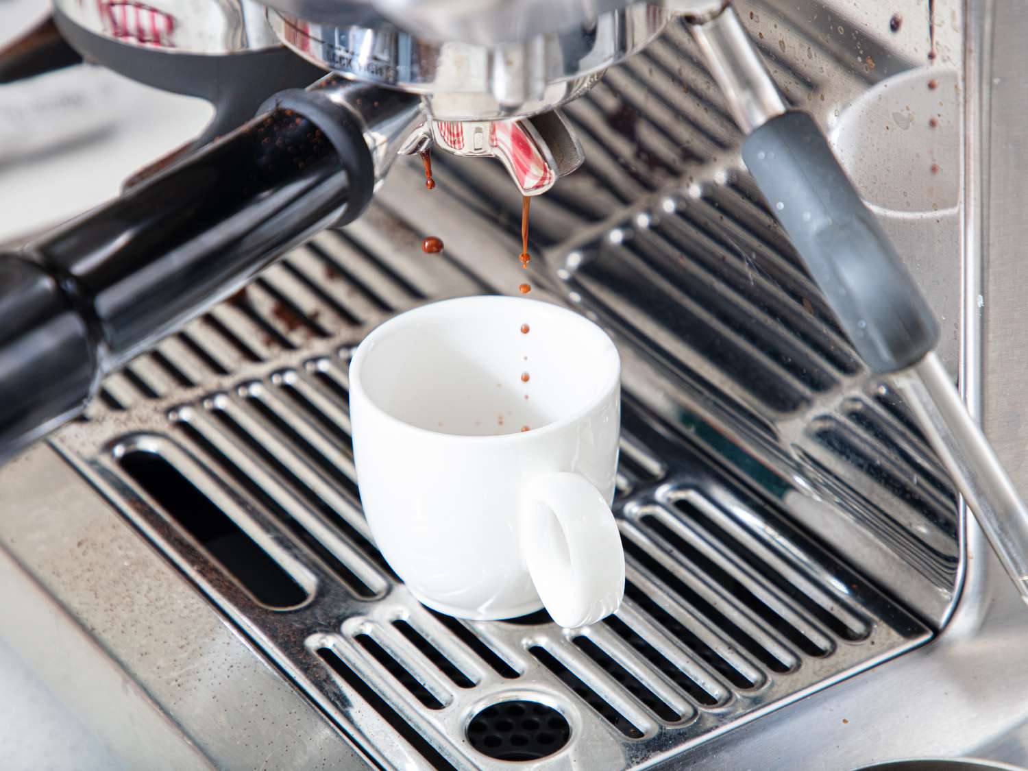 Espresso machine dispensing coffee into a white cup on a metal grate