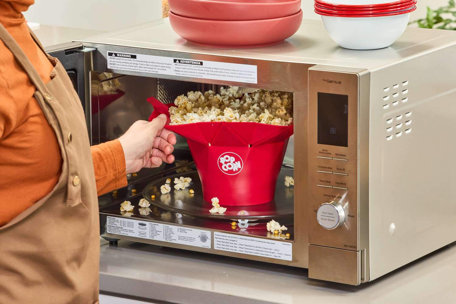 A person removes the Chef'n Pop Top Microwave Popcorn Maker from a microwave