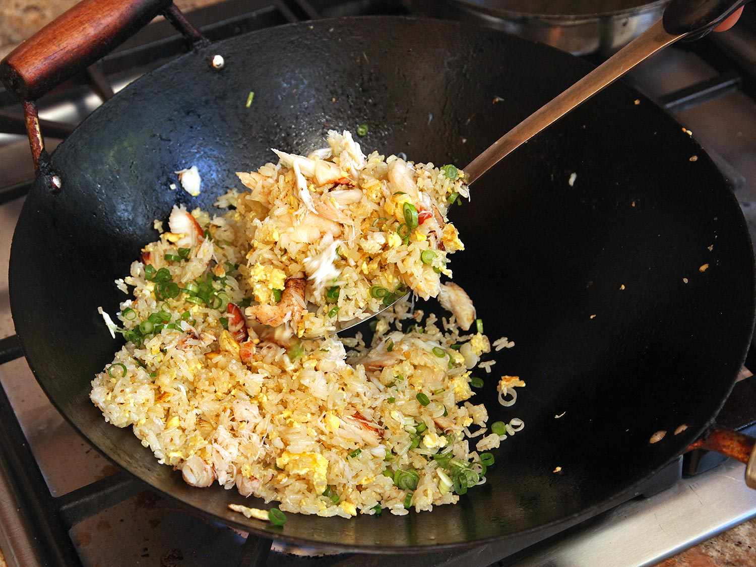 Crab and sliced scallion are mixed into the fried rice.