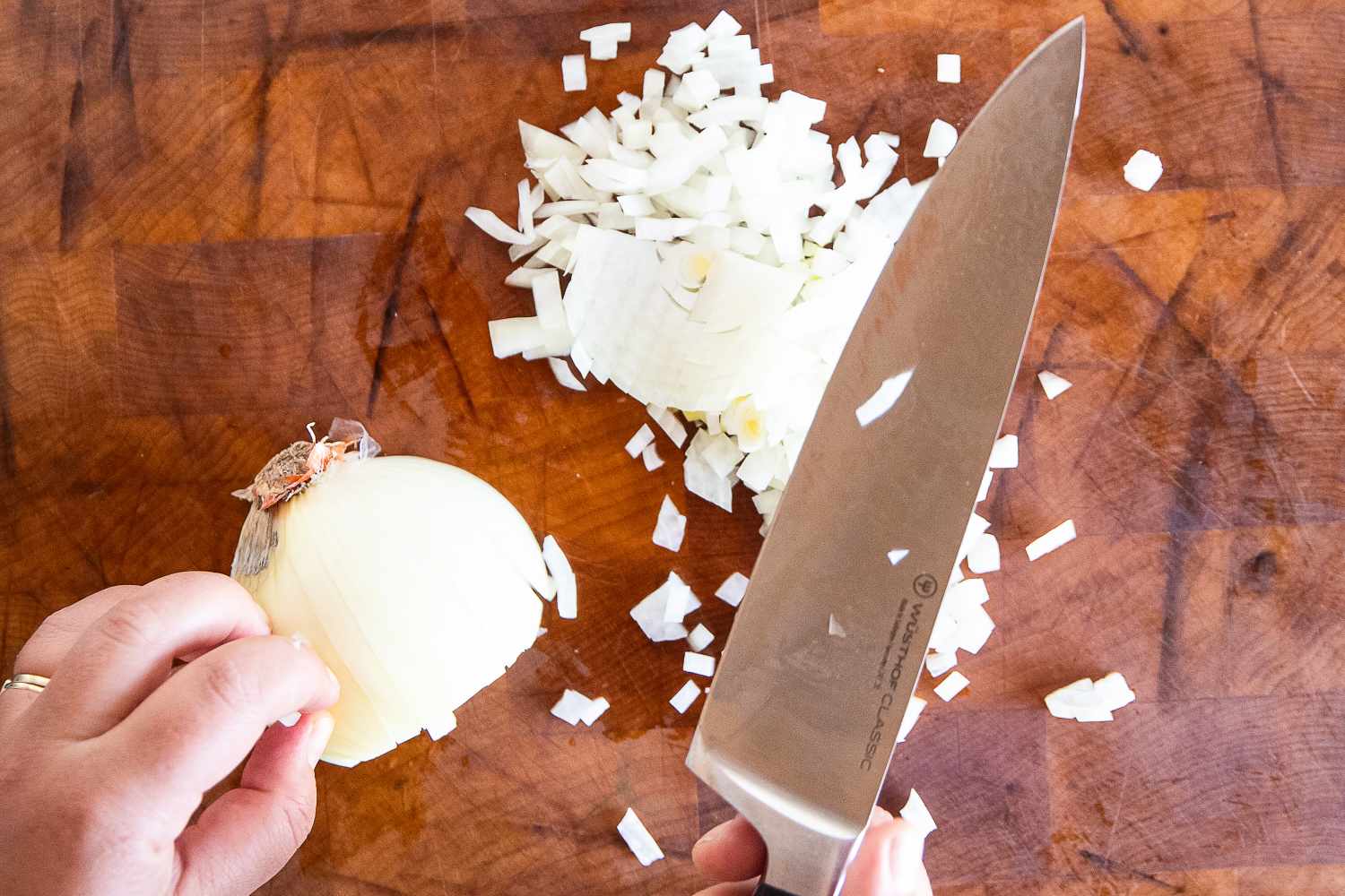 Chopped onion on a cutting board with a Wüsthof knife