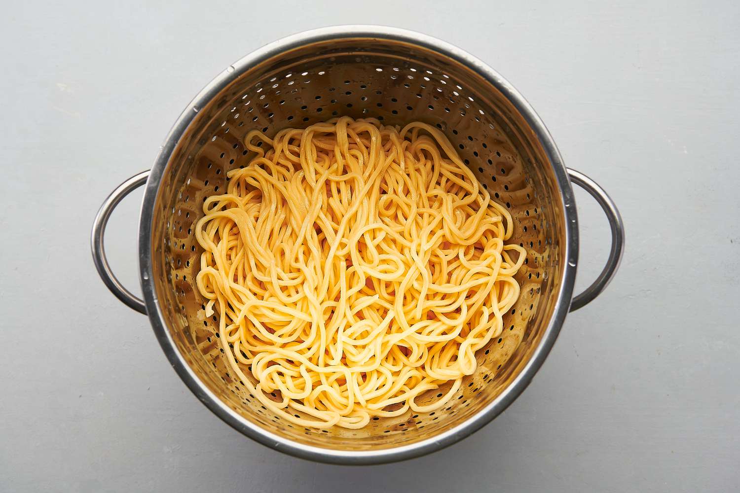 Al dente and separated noodles draining inside colander 
