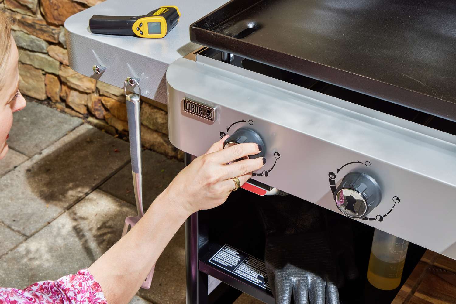 A person adjusts the temperature on the Weber 36 Inch Gas Griddle