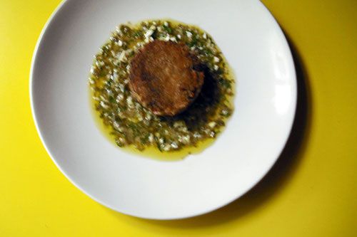 Overhead of a slice of fried pig's trotter terrine served on sauce gribiche.