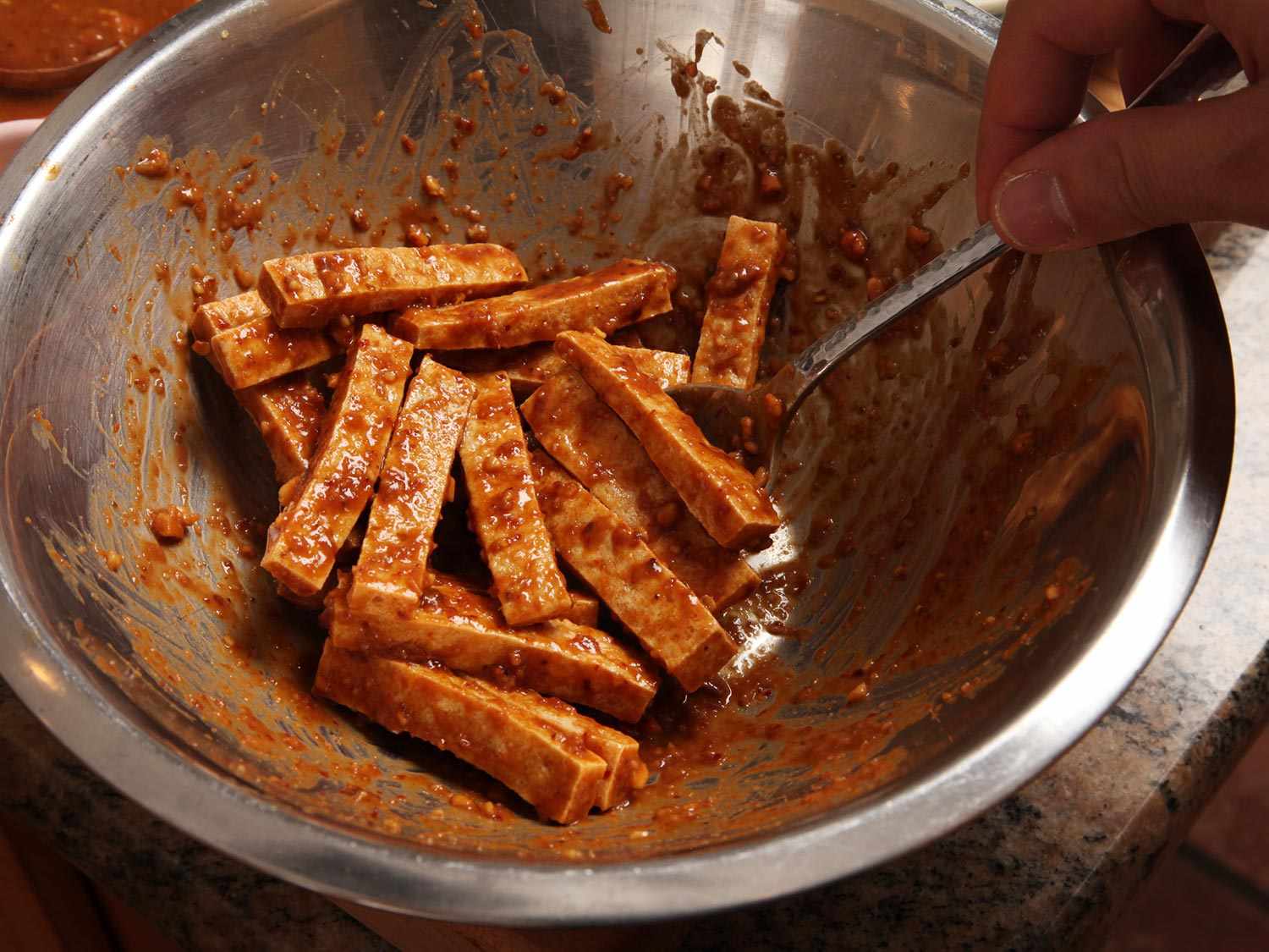 The fried tofu, cut into slender pieces, is tossed in some of the peanut-tamarind sauce.