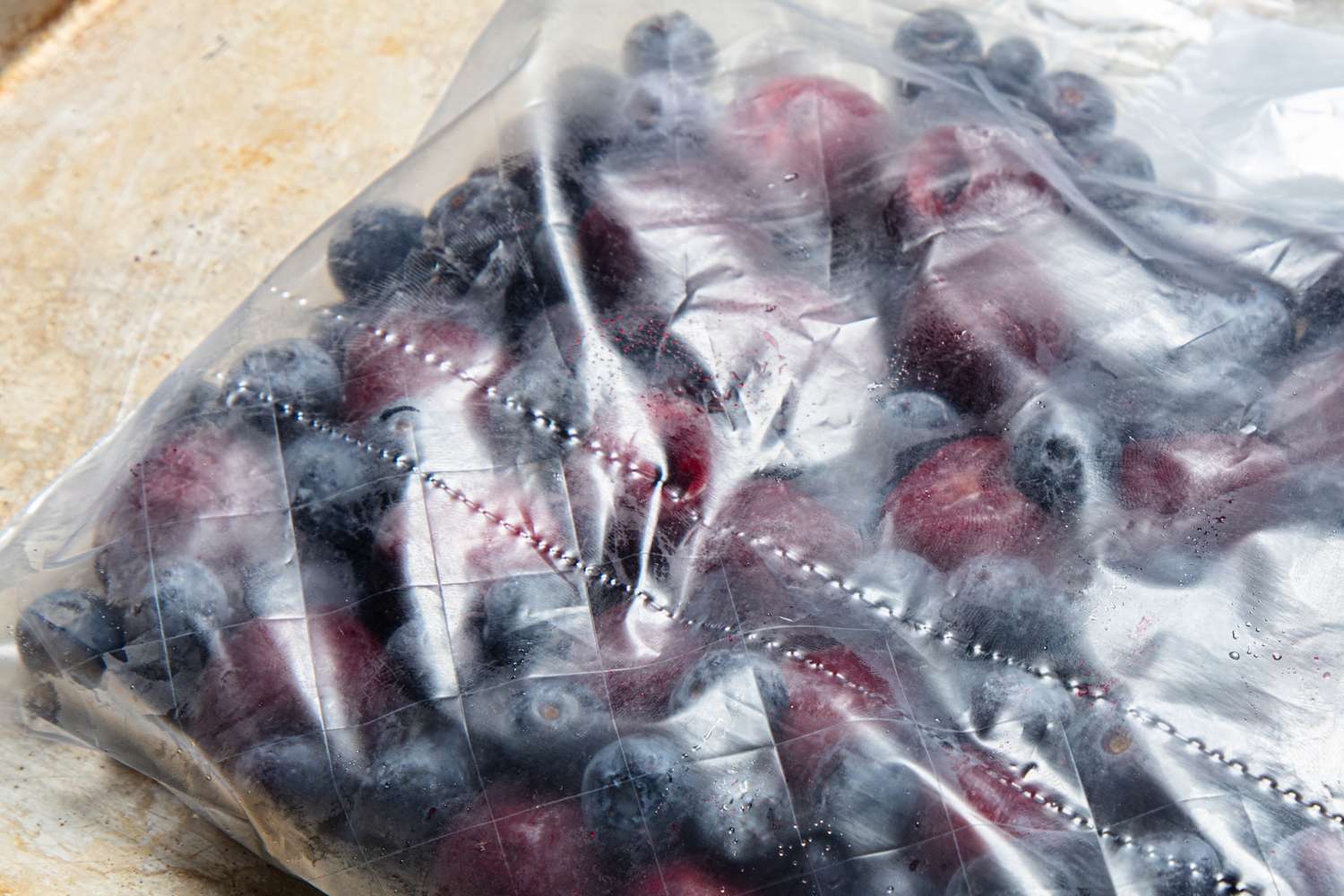 Frozen blueberries and raspberries inside a clear plastic bag
