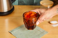 A person picking up a cortado glass.