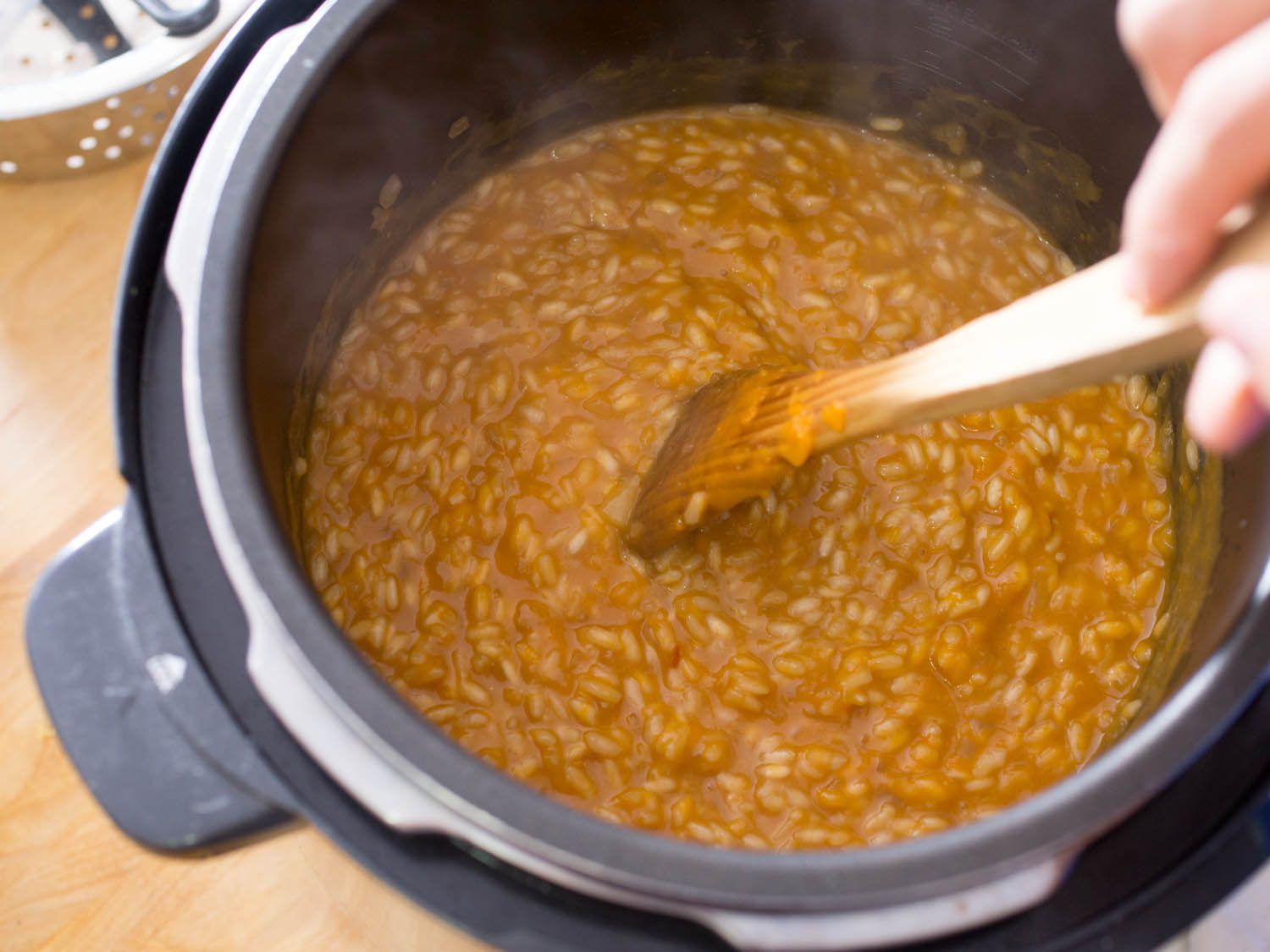 Stirring butternut squash risotto in a pressure cooker.